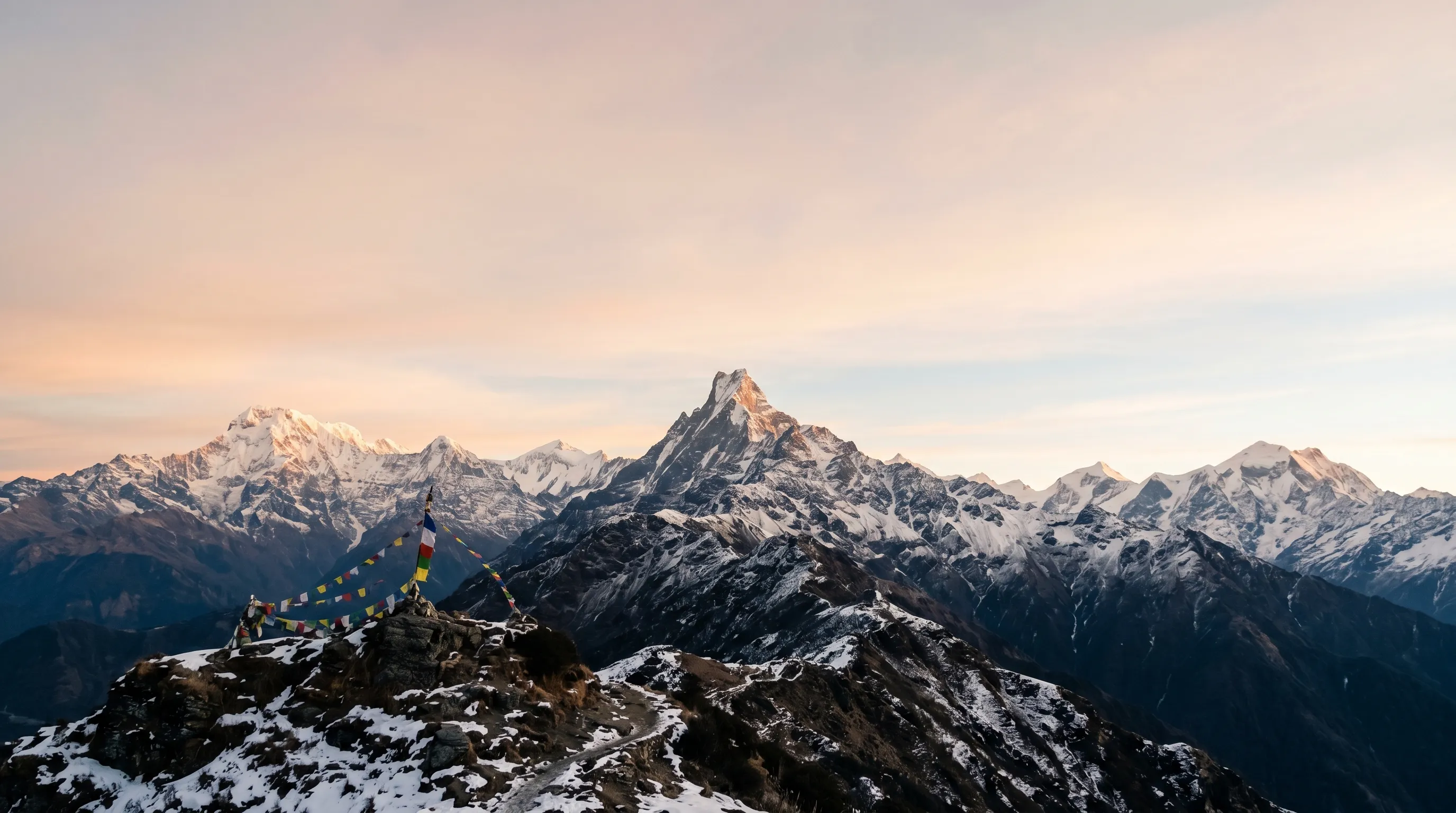 The Annapurna and Macchapuchhre (fishtail) ridgeline at dawn, with prayer flags on the foreground ridge.